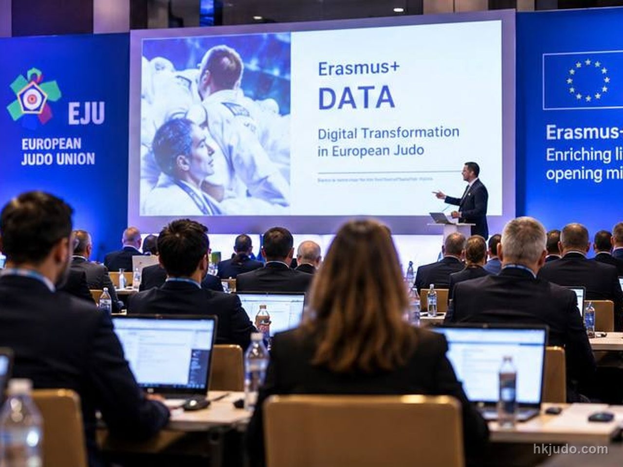講者在台上發言,背後屏幕顯示Erasmus+ DATA與Digital Transformation in European Judo,兩側為歐洲柔道聯盟及Erasmus+橫幅